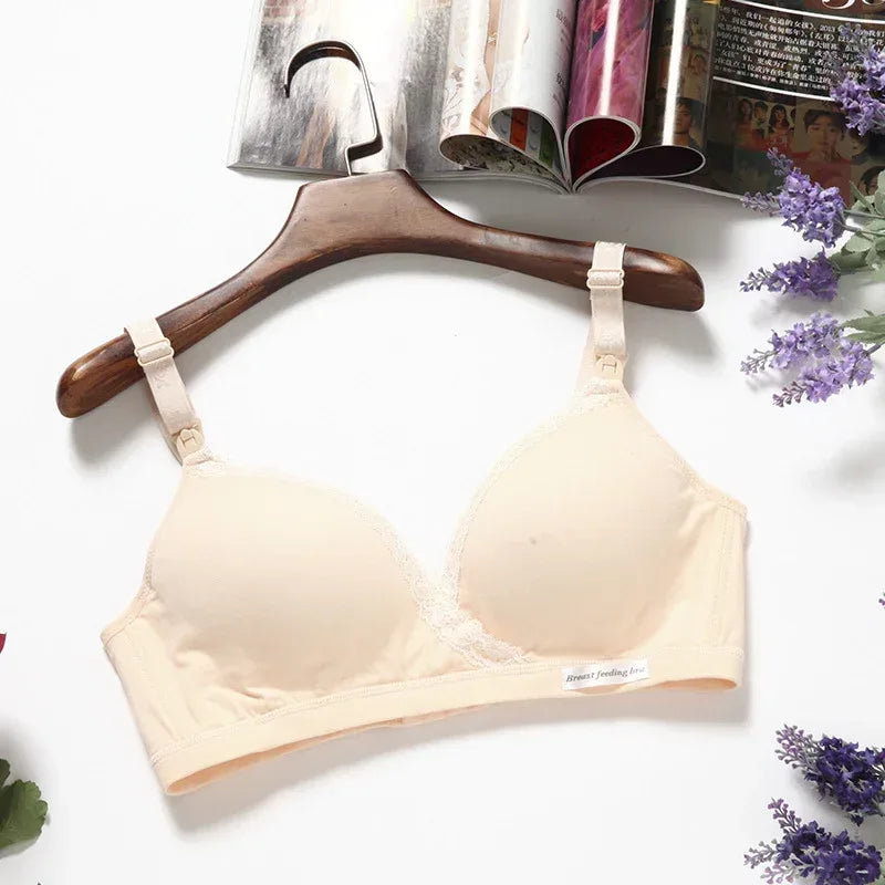 Cross-style breastfeeding bra in cream with lace trim and adjustable straps; on hanger