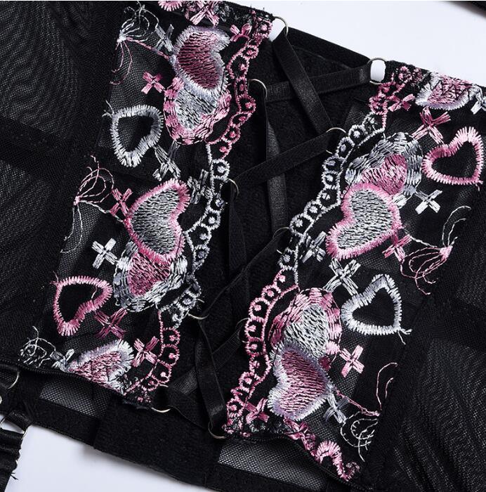 Close-up of black embroidered lingerie fabric with pink heart motifs and strap details