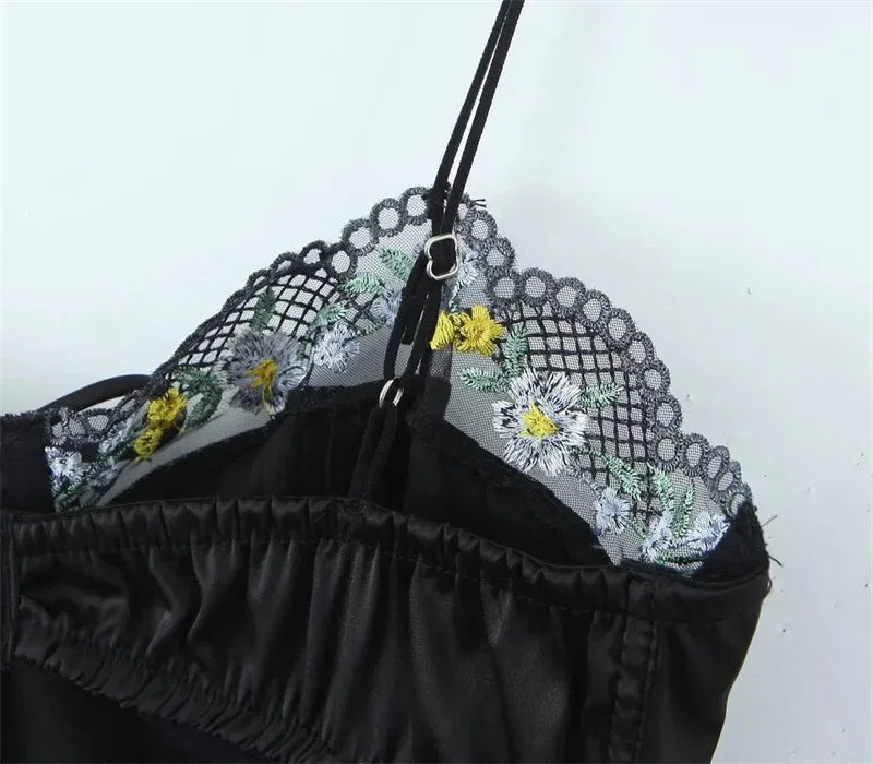 Close-up of embroidered lace bust with daisy accents and black adjustable shoulder strap