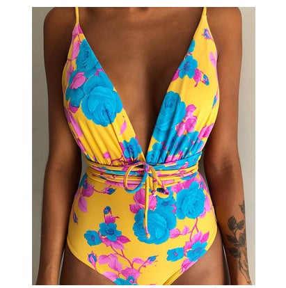 Backless monokini swimsuit with yellow base, blue floral print, and ring-tie belt