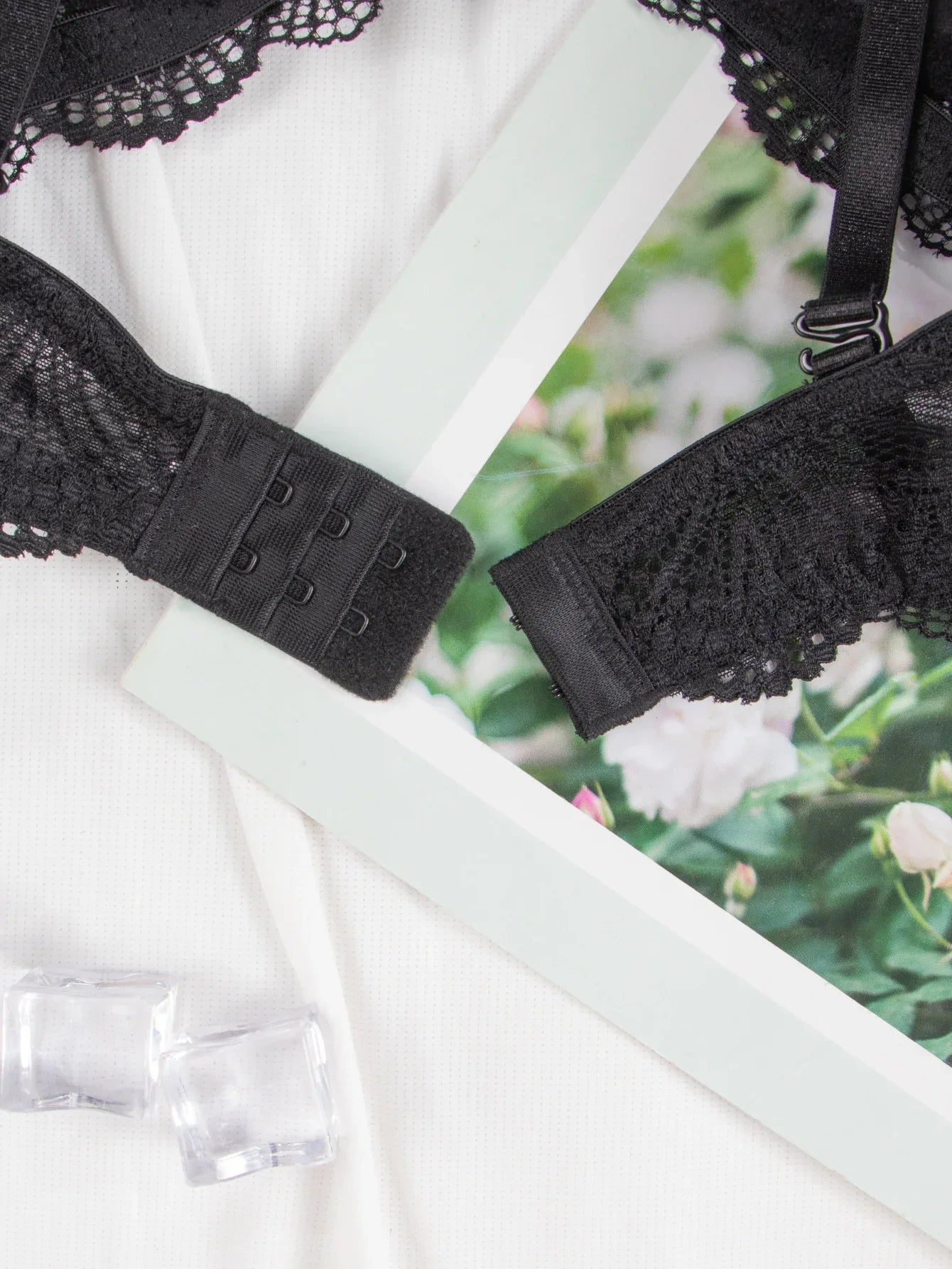 Black bra back band with hook-and-eye closure and lace-trim edges, adjustable strap