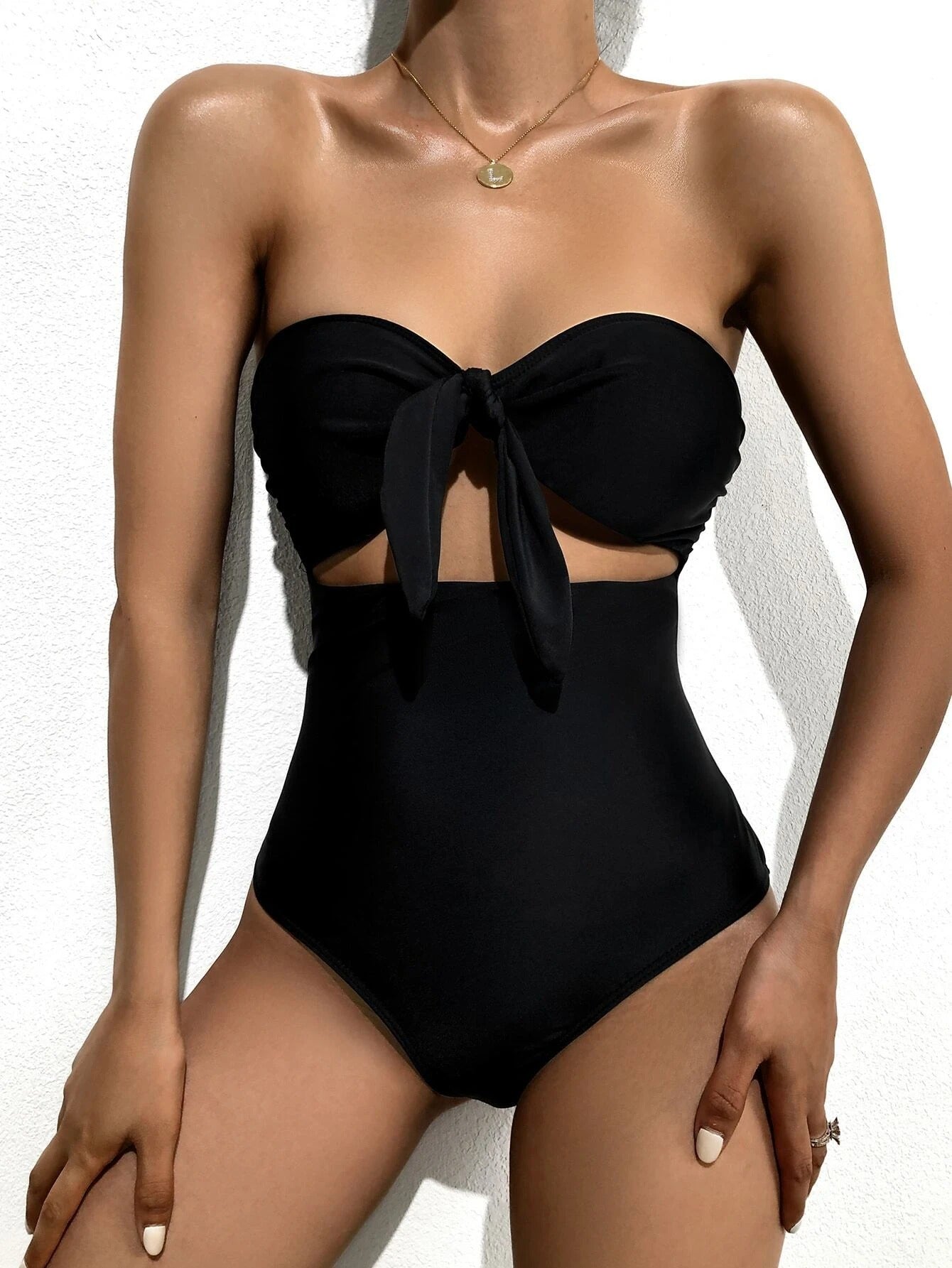 Black bandeau one-piece swimsuit with front bow and midriff cutout