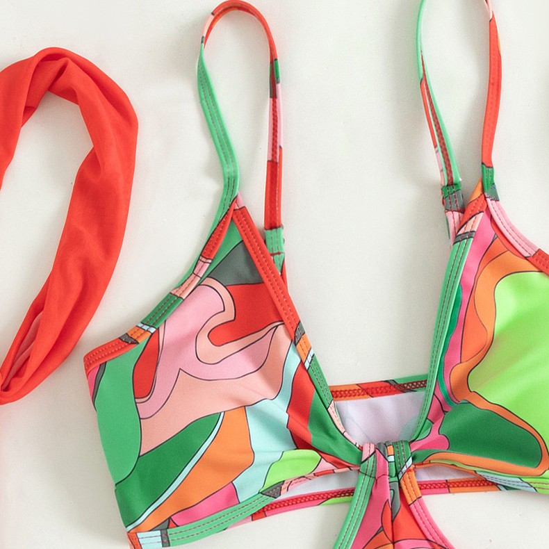 One-piece swimsuit close-up of halter straps and center tie, colorful retro abstract print