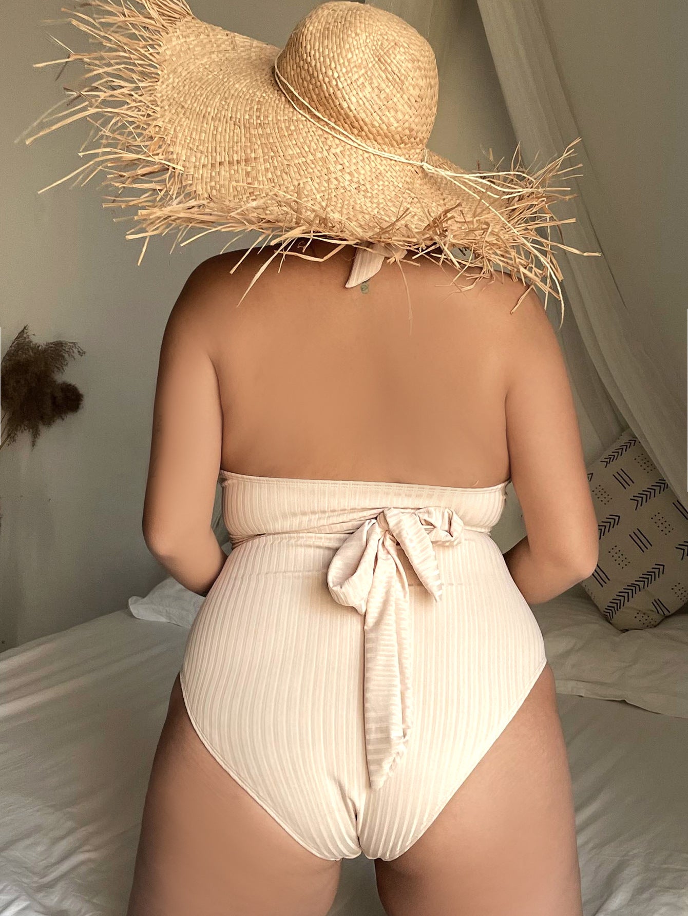 Beige ribbed one-piece swimsuit with gathered halter straps and bow tie at front waist