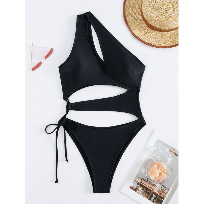 Hollowed-out one-shoulder one-piece swimsuit in black, flat lay with tie details.