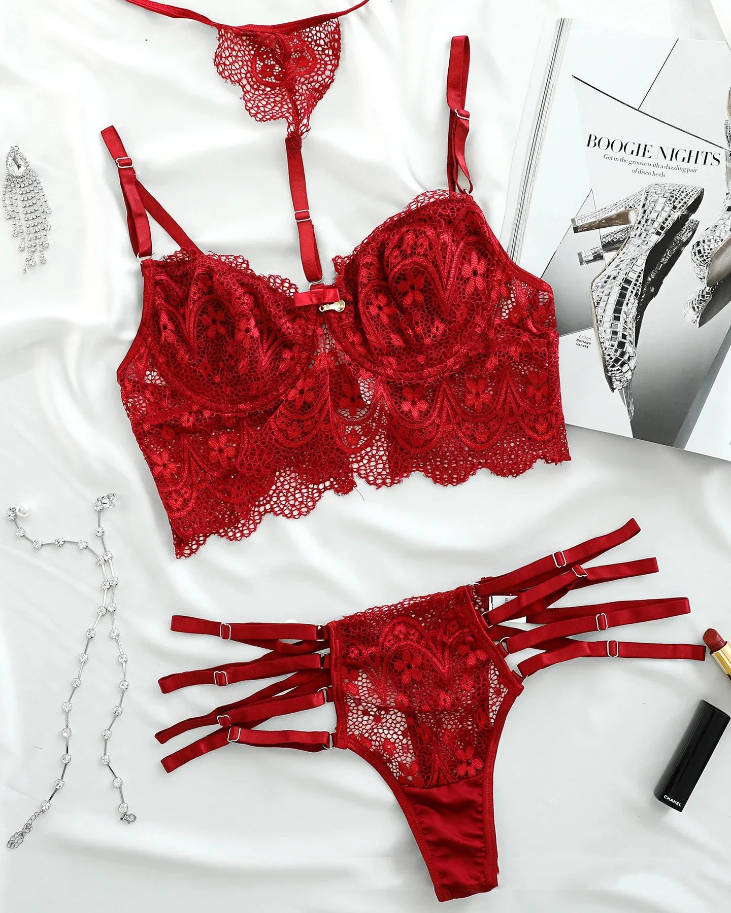 Red lace bra and strappy thong set laid flat with adjustable harness straps