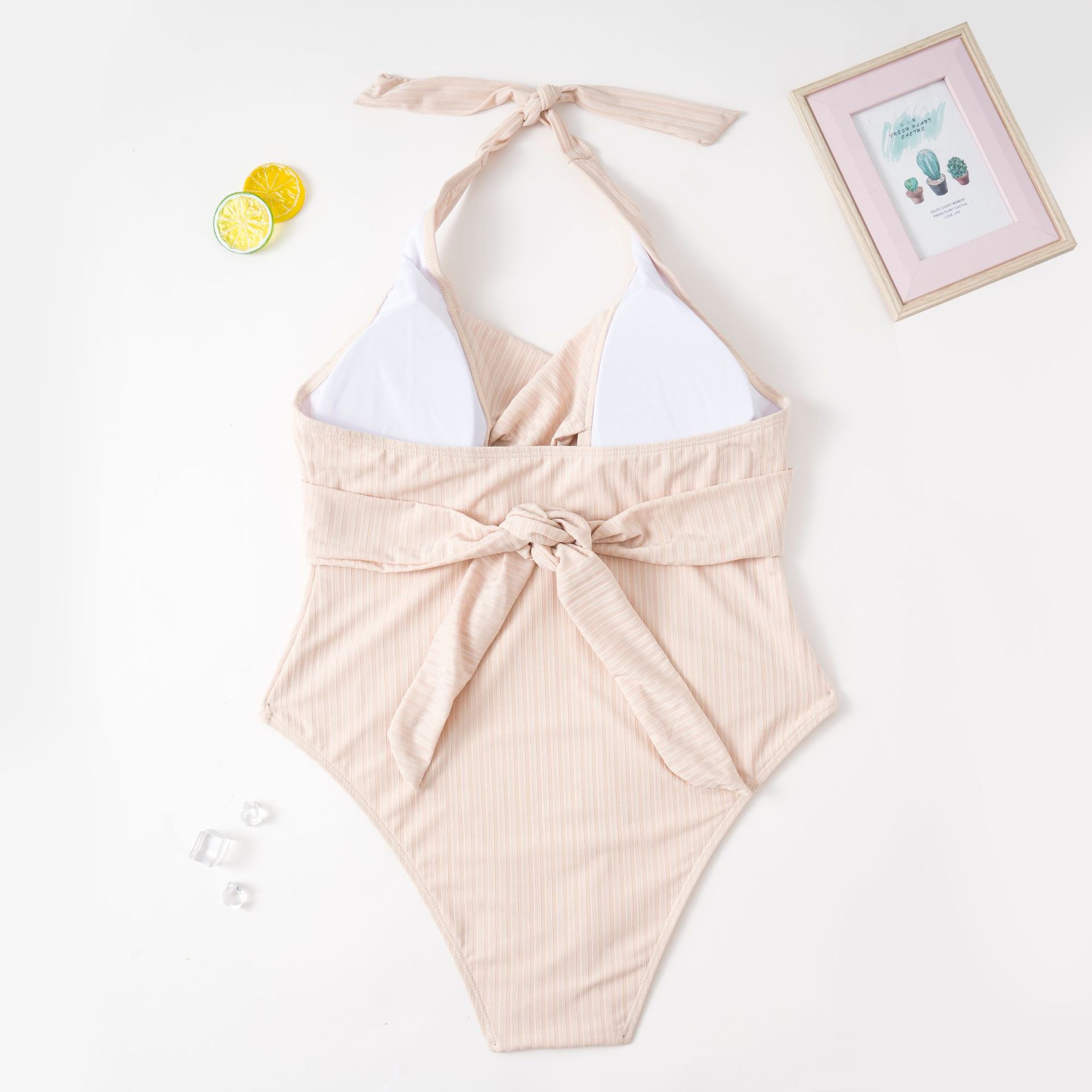 Beige ribbed one-piece swimsuit with halter straps and bow tie at waist
