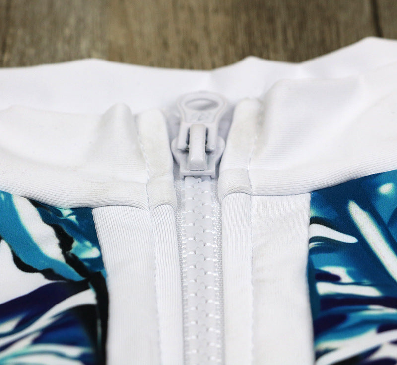 One-piece swimsuit close-up: white zipper and high neck trim with teal leaf print